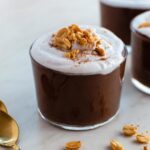 Chocolate peanut butter pudding served in a glass cup, and topped with whipped cream and crushed peanuts.