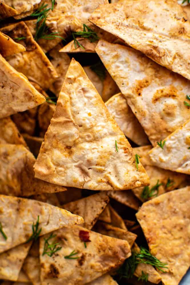 A close-up shot of air fryer pita chips sprinkled with chopped dill.