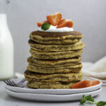 A stack of banana oat pancakes topped with yogurt, and strawberries.