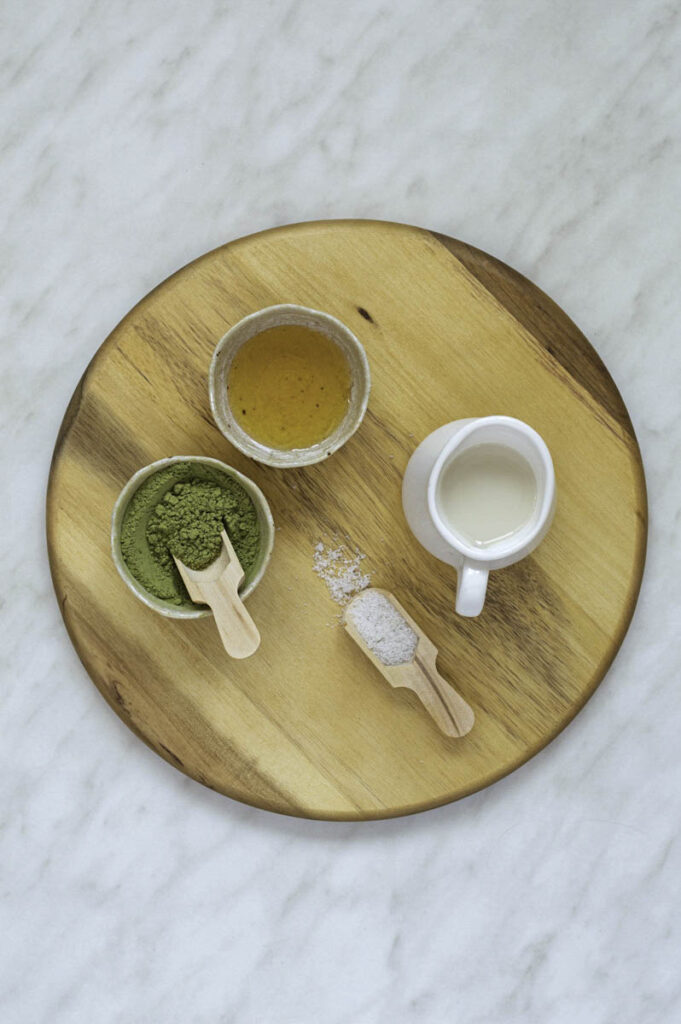 A wooden board with ingredients needed for matcha iced latte.