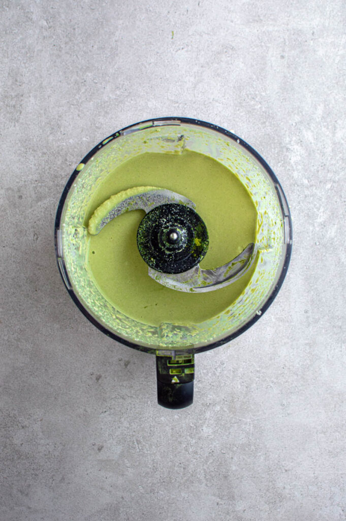 An overhead shot of a food processor bowl, filled with matcha frosting.