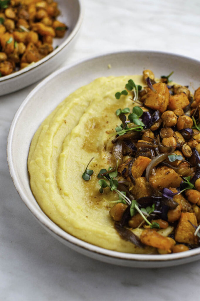 Cooked polenta plated in a bowl, topped with vegetables and chickpeas, and served for a dairy-free dinner