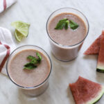 Two glasses of pink watermelon smoothie topped with mint leaves.