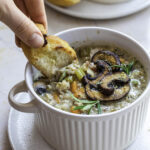 Dipping a piece of bread in a bowl of mushroom wild rice soup.