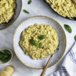 A blue bowl filled with orzo mac and cheese with a fork on the side of the bowl.
