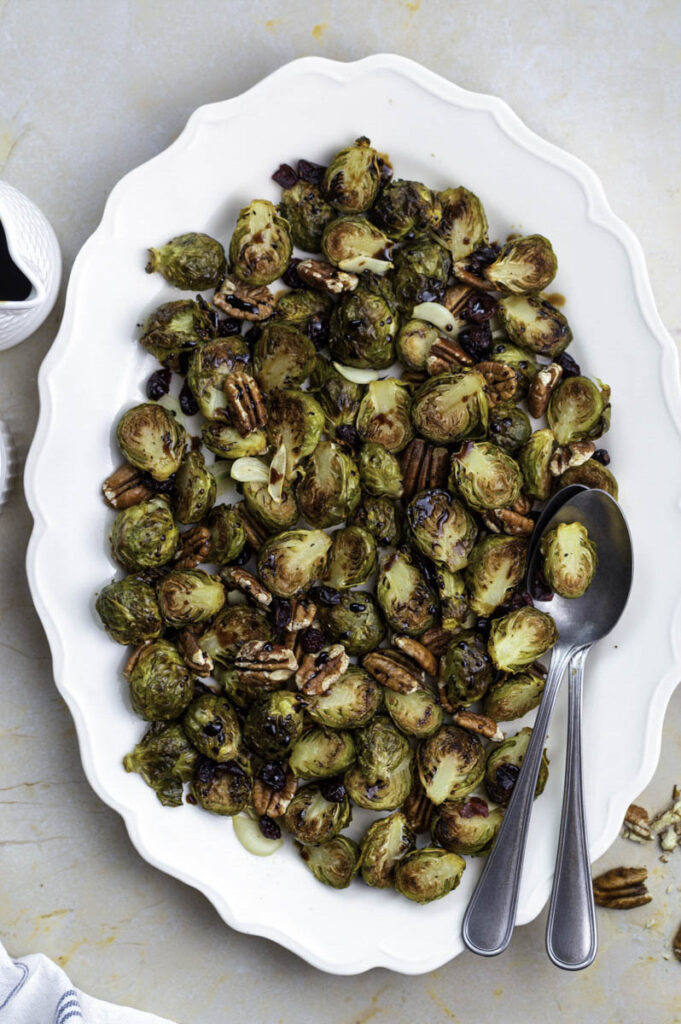Roasted brussels sprouts and pecans served on a white plate.