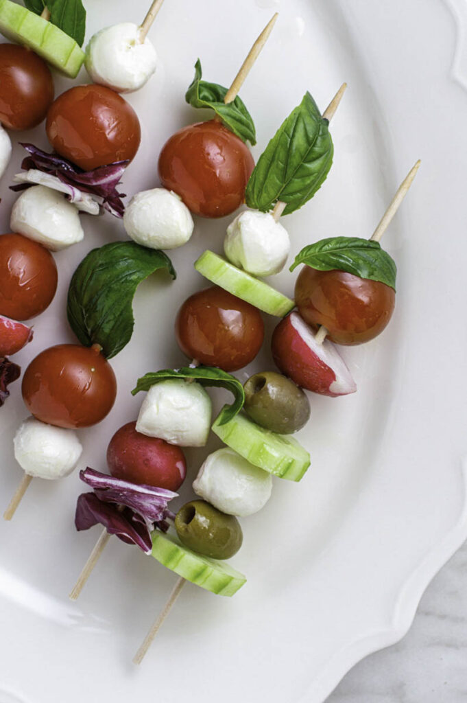 Five salad kabobs served in a white plate.