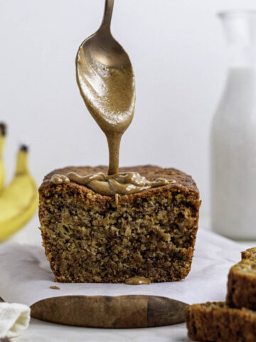 Pouring peanut butter with a spoon onto banana bread.