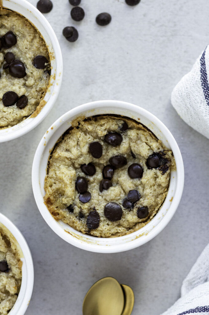 Baked vegan cookie in a white mug, topped with chocolate chips.
