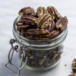 Roasted pecans in a clear jar.