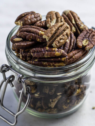 Roasted pecans in a clear jar.