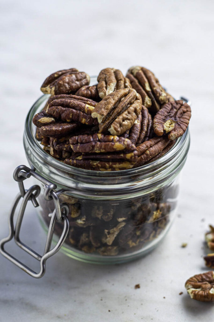 Roasted pecans in a clear jar.