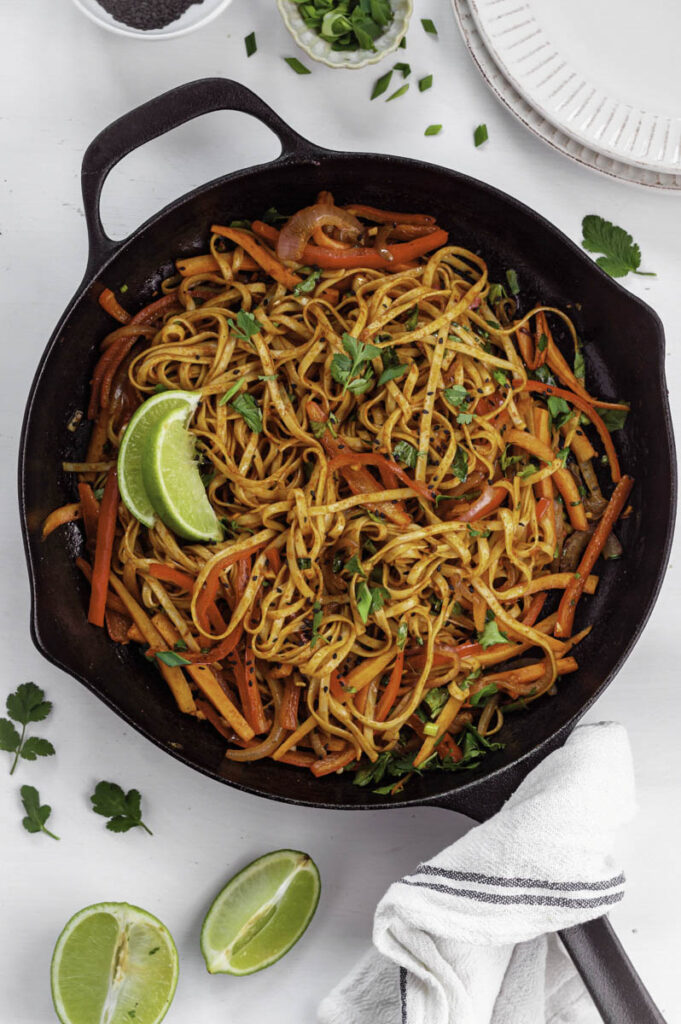 Garlic chili oil noodles in a black cast-iron skillet topped with cilantro.