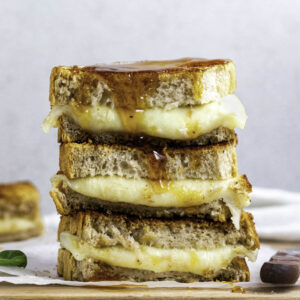 Three stacked provolone grilled cheese sandwiches over one another.