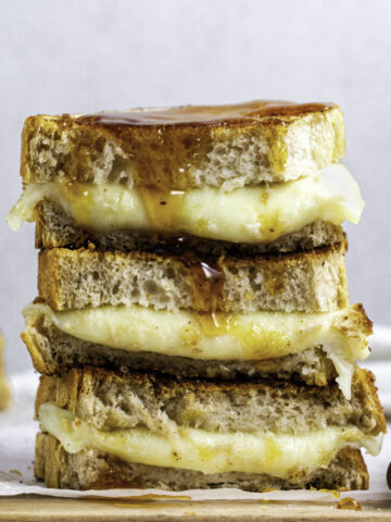 Three stacked provolone grilled cheese sandwiches over one another.