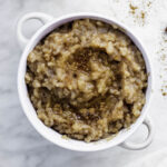 Oat milk rice pudding served in a white bowl and topped with ground cinnamon.