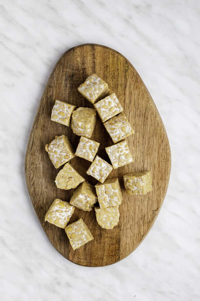 A wooden board with cubed tempeh pieces.