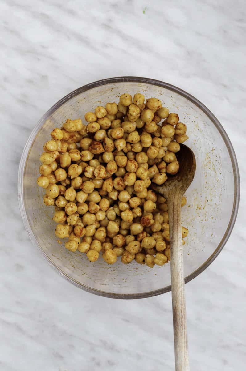 Chickpeas in a clear bowl tossed with spices and oil.