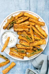 Air Fryer Zucchini Fries served with herbed yogurt dip on a white plate.