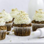 Five carrot cake cupcakes on a marble platter, topped with carrot cake frosting without cream cheese.