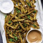 Five guys Cajun fries served on a baking sheet layered with parchment paper and topped with parsley.