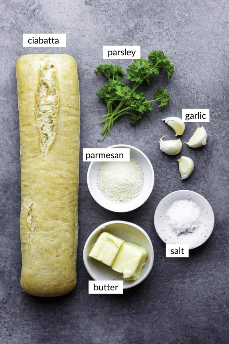 Gathered ingredients for making our garlic ciabatta bread recipe, with text overlay on each ingredient.