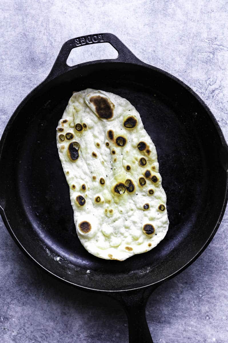 Cooked naan bread without yogurt in a cast-iron skillet.