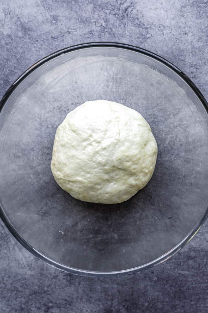 Kneaded naan dough in a greased mixing bowl.