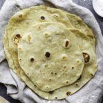 Flour tortillas in a plate layered with a kitchen towel.