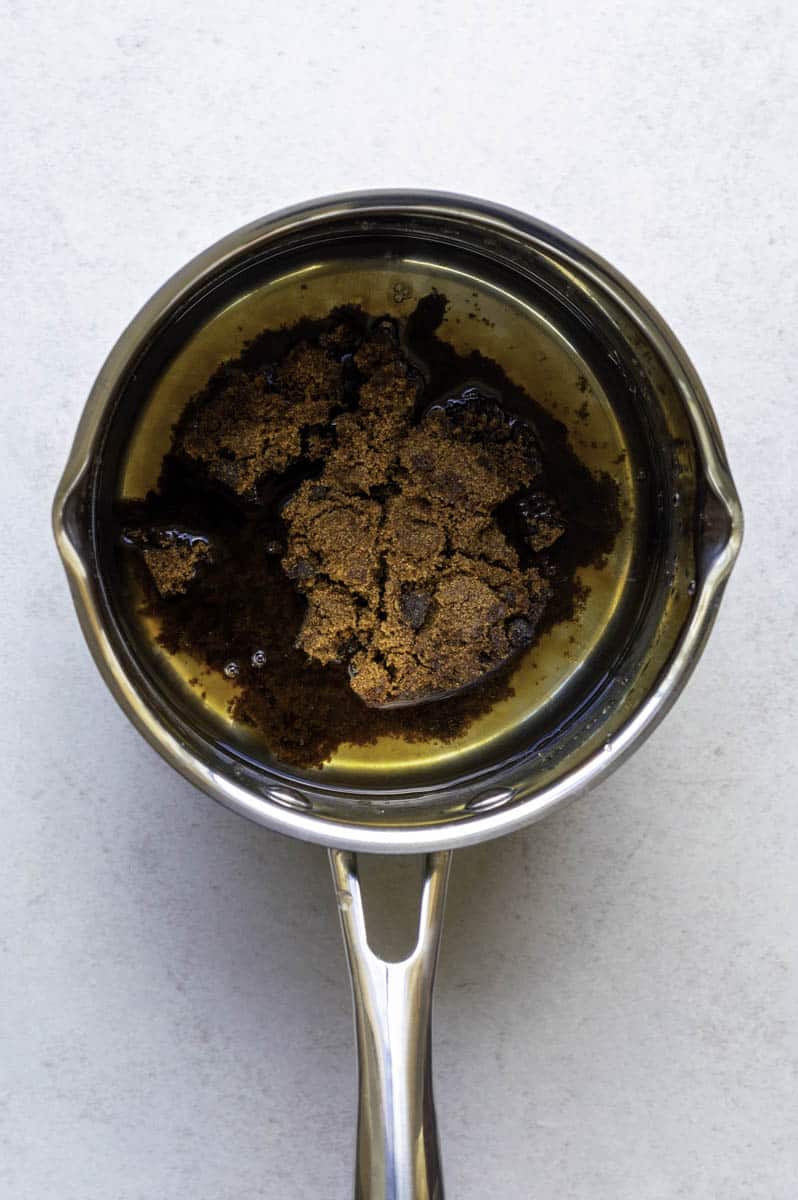 Dark brown sugar and water in a stainless-steel saucepan.