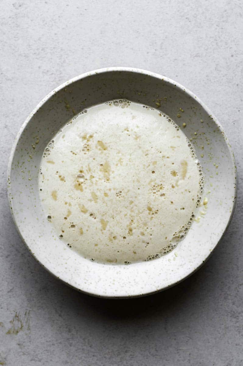 Bloomed yeast mixture in a small white bowl.