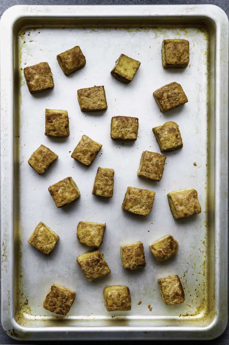 Crispy baked tofu cubes on a silver baking sheet.