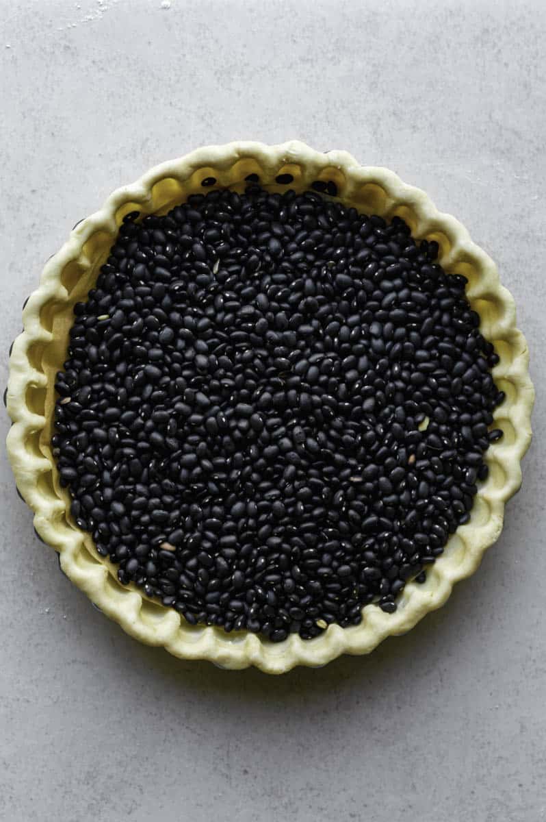 Unbaked pie crust filled with back beans.