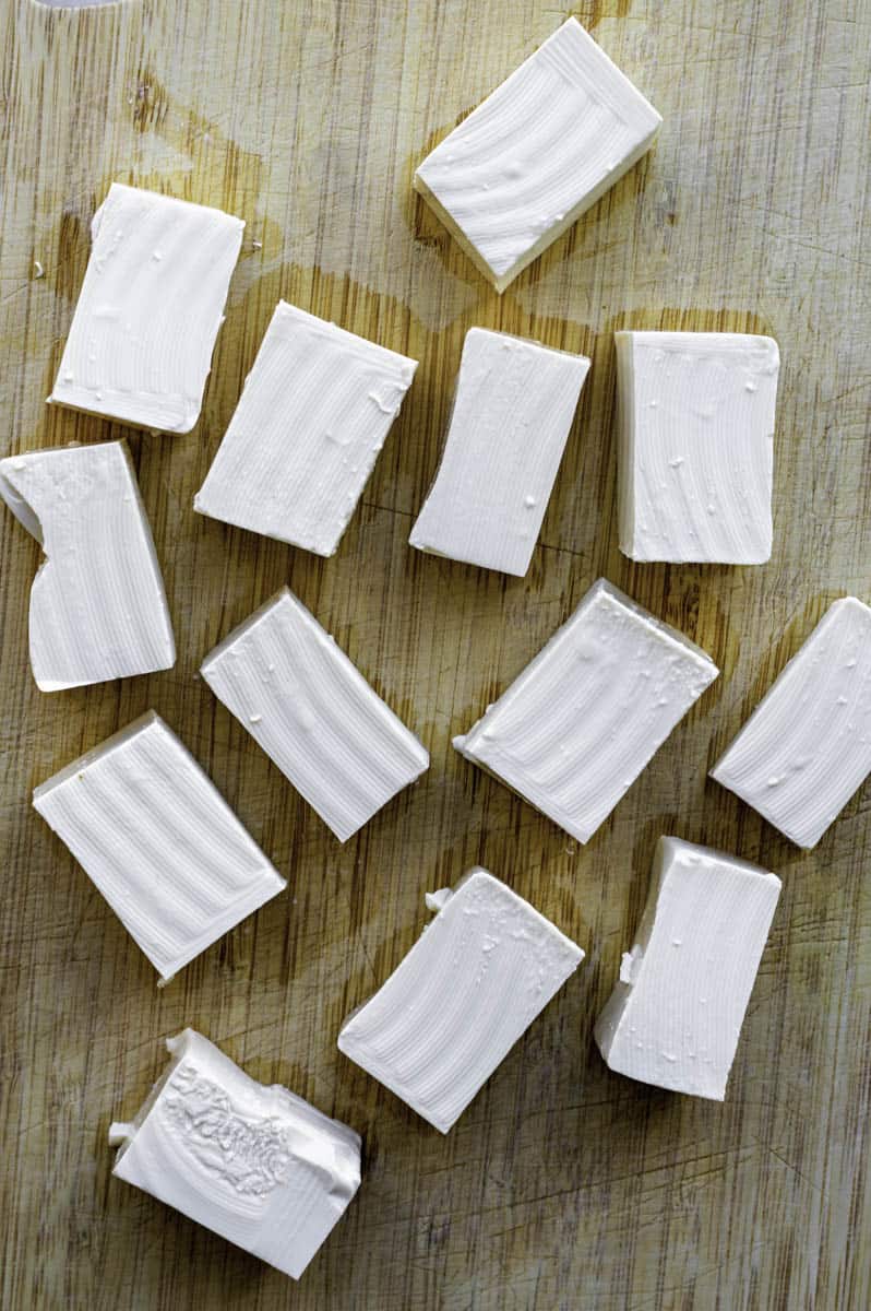 Tofu cubes on a wooden cutting board.