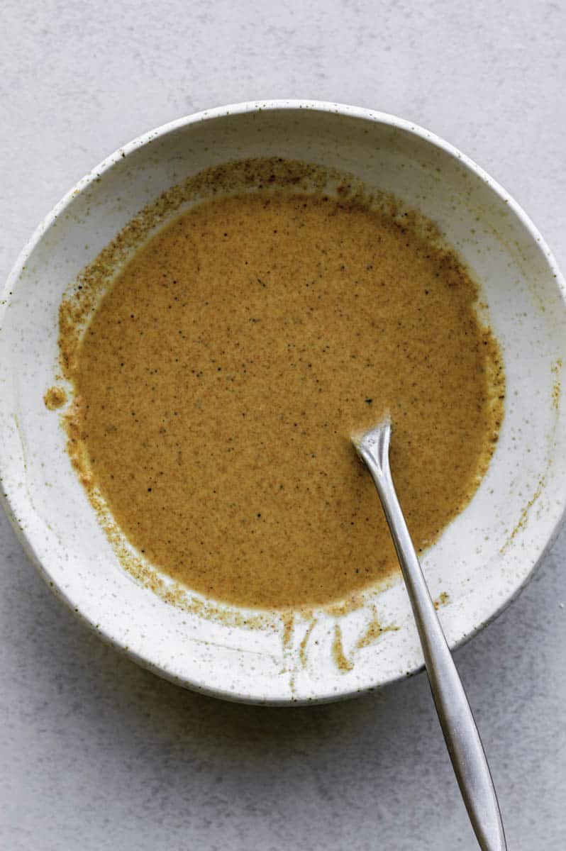 Coating batter in a white bowl with a fork in it.