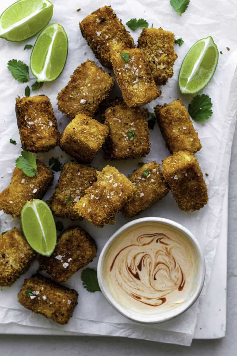 Fried silken tofu cubes served on a piece of parchment paper, and topped with sea salt and fresh cilantro.