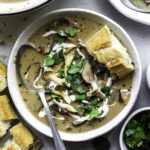 Oyster mushroom soup served in a white bowl and topped with fresh cilantro.