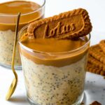 Biscoff overnight oats served in a glass cup and topped with more biscoff spred and a Lotus cookie.