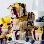 Three vegan lemon blueberry muffins stacked on top of each other and garnished with lemon zest.