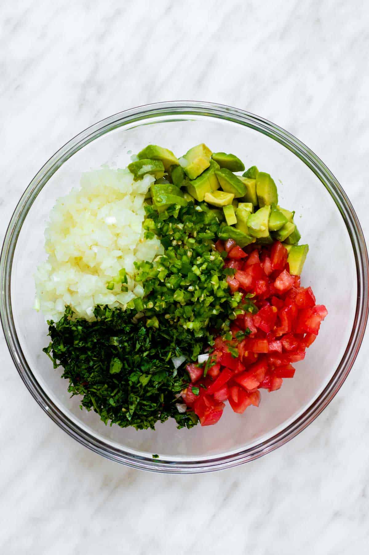 Ingredients for avocado pico de gallo added to a large glass bowl.