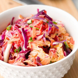 Vegan Coleslaw without mayo in a white bowl on a wood board.
