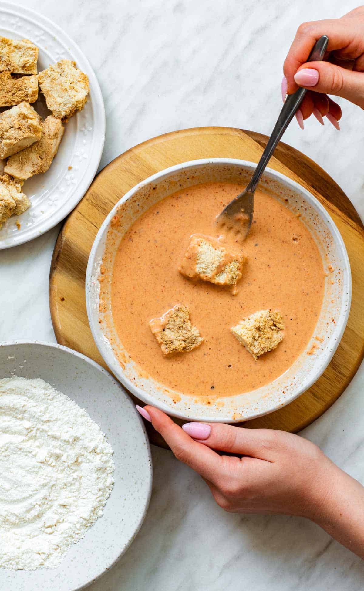 Battering tofu pieces in a mixture made out of flour and spices.