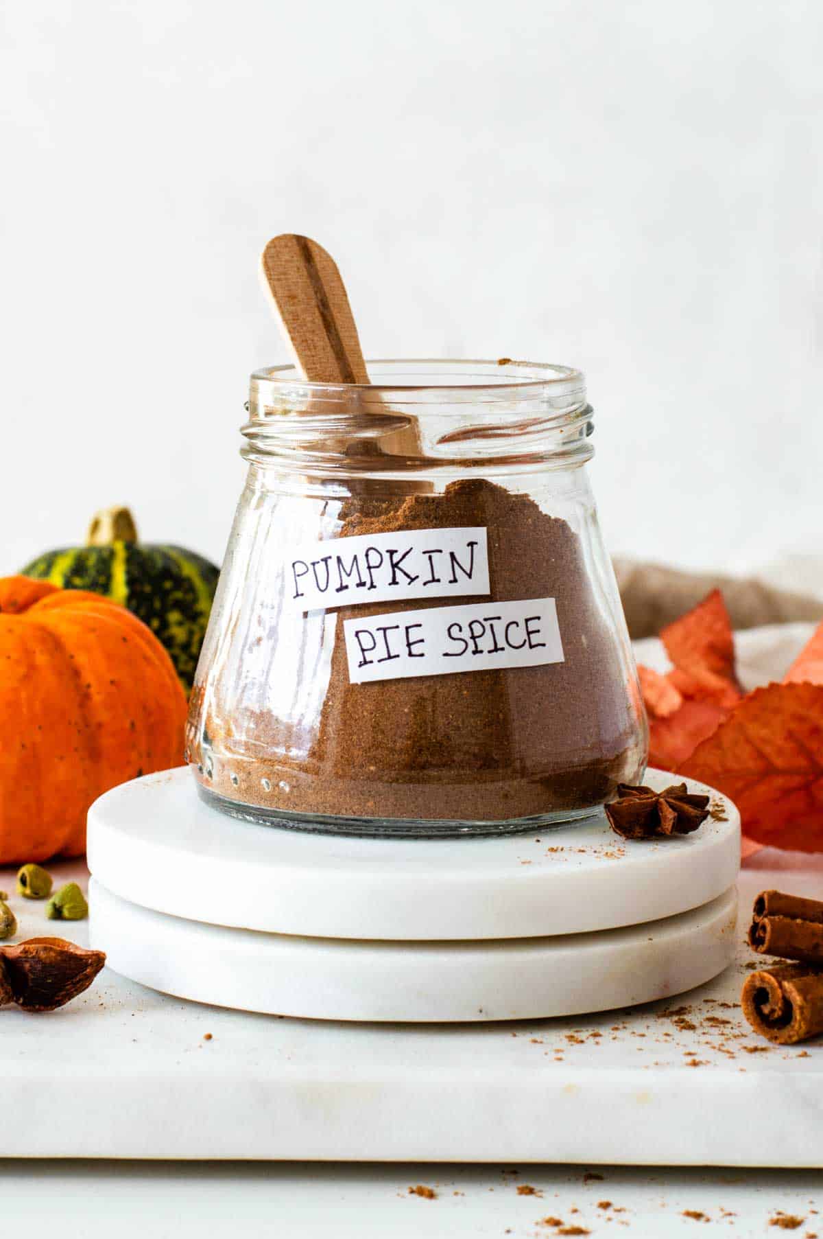 A small jar filled with pumpkin pie spice and placed over two marble coffee cup pads.