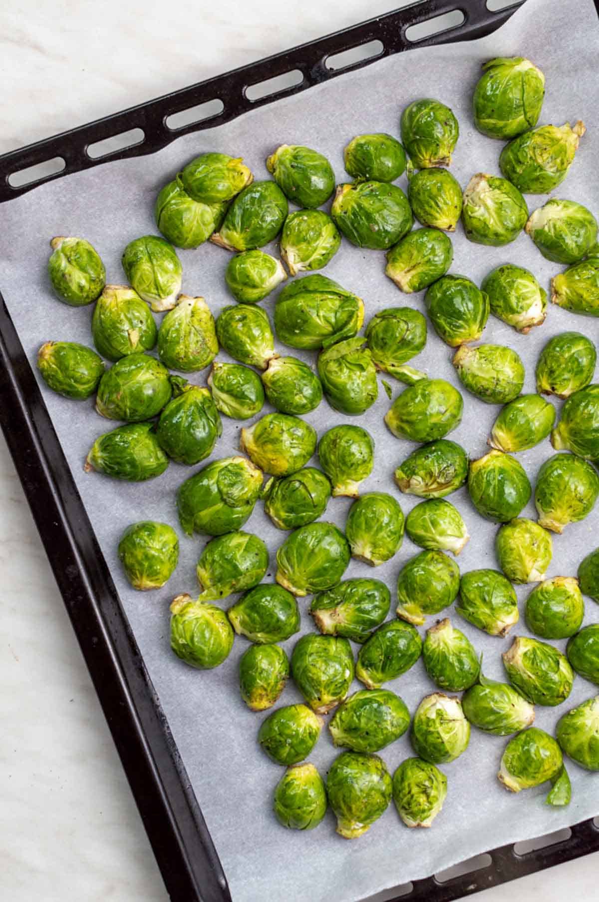 Halved frozen Brussels sprouts on a baking sheet.