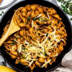 French onion pasta serve in a cast-iron skillet and topped with shredded cheese and fresh thyme.