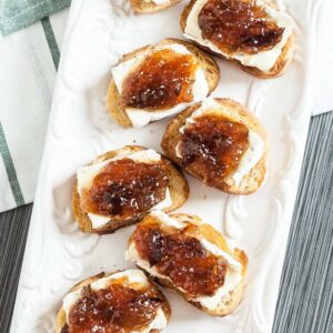 Brie and fig crostini served on a white platter.