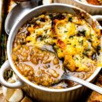 A spoon dipped into a bowl filled with French onion soup.