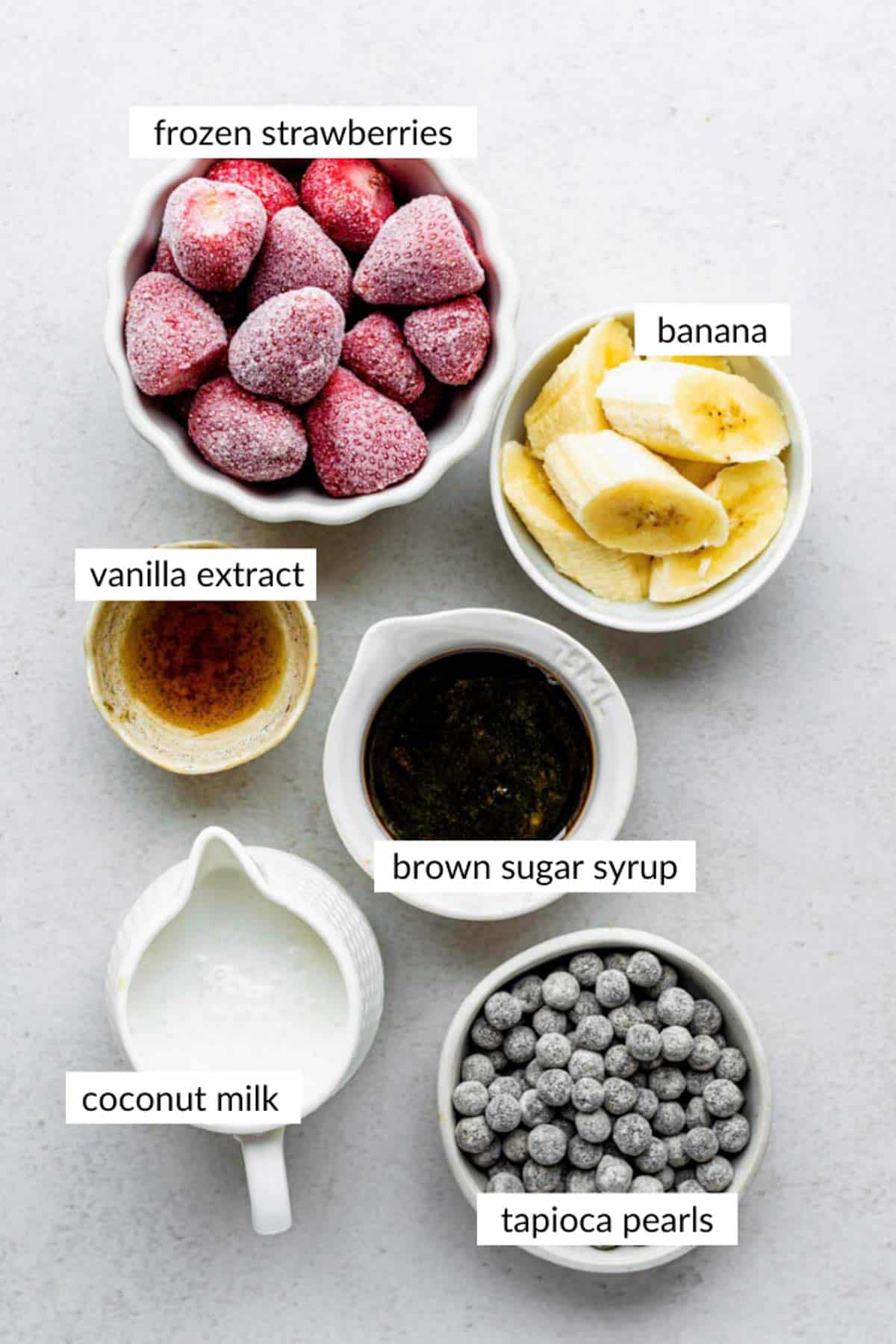 Gathered ingredients for making boba tea smoothie with text overlay on each ingredient.