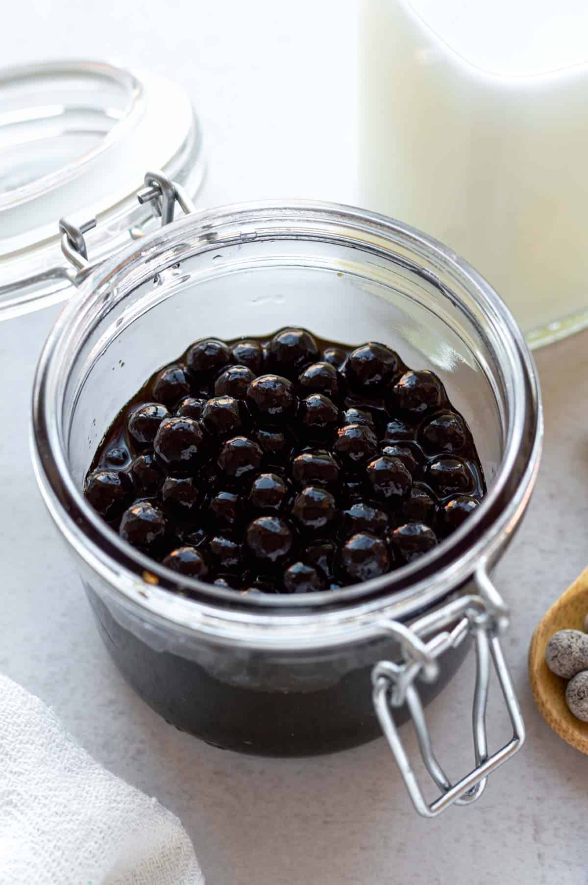 Cooked boba coated with brown sugar syrup in a glass jar.