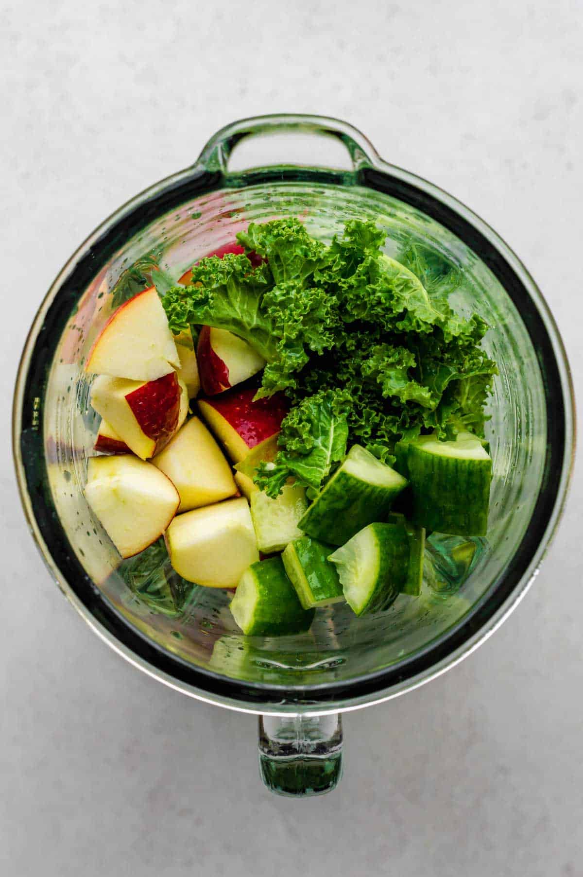 Ingredients for kale juice in a blender jar.